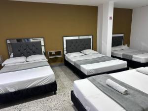 a room with three beds in a room at hotel guayacanes central in Medellín
