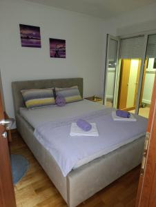 a bedroom with a large bed with purple pillows on it at Apartman TEA Trebinje in Trebinje