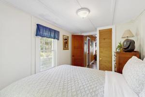 a bedroom with a white bed and a window at Sebago Shores Cottage in North Sebago