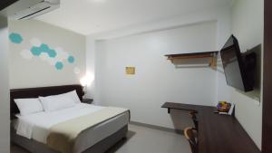 a bedroom with a bed and a desk and a television at Hospedaje Diamantes in Huacho