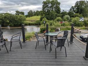 a table and chairs on a deck next to a river at Hal`s at Killynick in Killyhevlin