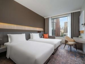 two beds in a hotel room with a window at Mercure Bangkok Siam in Bangkok