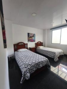 a bedroom with two beds and a window at Hotel Siglo 21 in Cali +6 photos