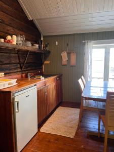 a kitchen with a table and a white refrigerator at Cottage from 1850 in Ballstad in Ballstad +11 photos