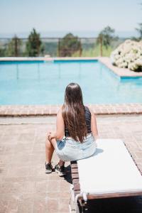 a woman sitting on a bench by a pool at La Domanda Hostería in Villa Berna