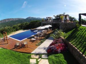 a wooden deck with chairs and a swimming pool at Solar Da Serra Tiradentes in Tiradentes