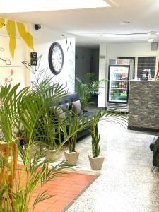 a lobby with a clock on the wall and plants at hotel guayacanes central in Medellín