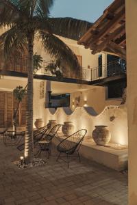 a patio with chairs and a table and a palm tree at Villa Mineli in Campeche