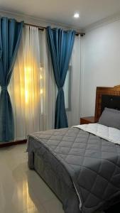 a bedroom with a large bed with blue curtains at Dk Casa in Lusaka