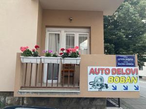 a house with a balcony with flowers and a sign at Sladjana apartman in Prijepolje