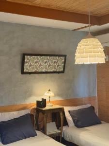 two beds in a room with a table and a window at 愛犬と泊まれる宿 ほこほこsaza 一棟貸し 海も川も徒歩圏内 dog run付き 釣りの穴場 サーフィン 自然 満点星空 蛍鑑賞 最大7名 in Miyazaki