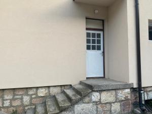 a white door on a building with a stone wall at Sladjana apartman in Prijepolje