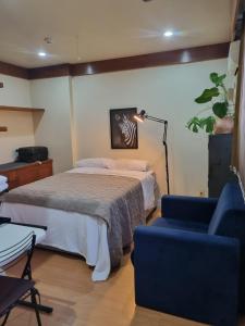 a bedroom with a bed and a blue chair at Flora e Fauna in Porto Alegre