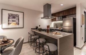 a kitchen with a counter with chairs and a kitchen island at Casa Grijalva by Kukun Apartments in Mexico City