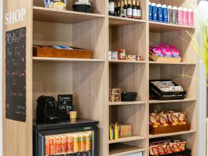 a kitchen with a shelf filled with food and drinks at Aparthotel Adagio Access Paris Asnières in Asnières-sur-Seine