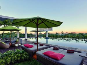 a pool with two beds and an umbrella at Mercure Serpong Alam Sutera in Serpong