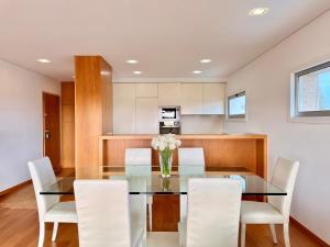 a dining room with a glass table and white chairs at T2 Dunas Esposende in Esposende +36 photos
