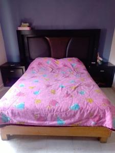 a bed with a pink comforter on top of it at House near AIFA in San Cristóbal