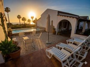 a patio with white chairs and a swimming pool at Residenza il Normanno - La terrazza sul mare in Santa Domenica