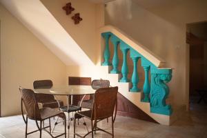 a dining room with a table and chairs under a staircase at Morada Coral Hostel em Maracaípe in Porto De Galinhas
