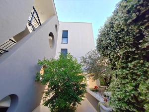 a white building with trees and plants in front of it at Maboka Studio in Zadar