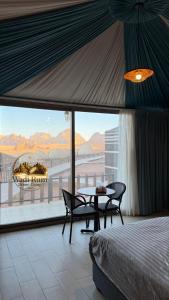 a bedroom with a bed and a table and a large window at Wadi Rum Dome Camp in Disah