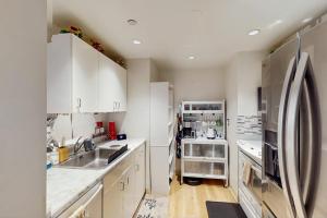 a kitchen with white cabinets and a stainless steel refrigerator at City Lights at Newmark - World Cup Availability in Seattle