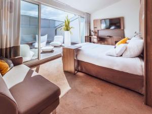 a bedroom with a large bed and a living room at Novotel Toulouse Centre Wilson in Toulouse