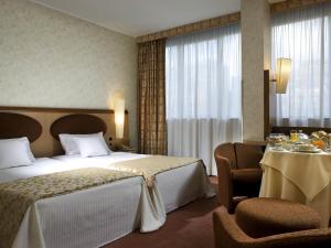 a hotel room with a bed and a table and chairs at Mercure Roma West in Mostacciano +153 photos
