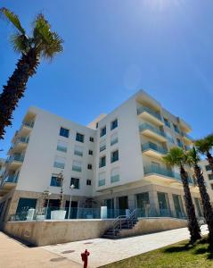a large white building with palm trees and a fire hydrant at Atlantic Blue 3BR Ocean View, Rabat Corniche in Rabat