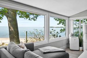 a living room with a couch and a view of the ocean at Crystal Beach Waterfront Cottage - Sunset Views in Fort Erie