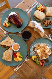 ein Holztisch mit Tellern mit Frühstücksspeisen darauf in der Unterkunft Amet Hotel Boutique in La Paz