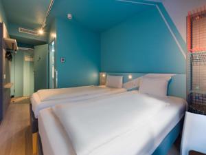 two beds in a room with a blue wall at ibis budget Hamburg City in Hamburg