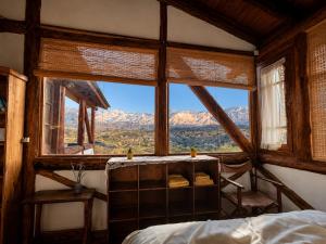 a bedroom with a bed and a large window at Cabaña El Cóndor in Potrerillos