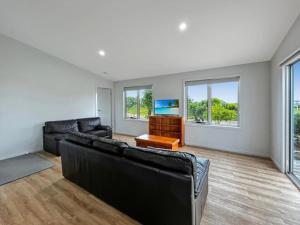 a living room with black leather furniture and a flat screen tv at Snapper Cabin in Portland