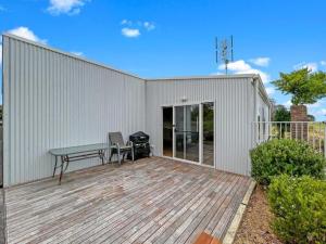 a white building with a picnic table on a deck at Snapper Cabin in Portland +2 photos