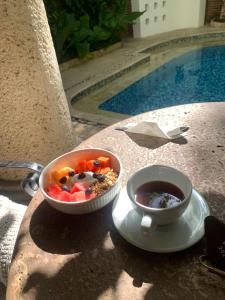 a bowl of cereal and a cup of coffee next to a pool at Hotel Boutique Patio Corao by GEH Suites in Cartagena de Indias