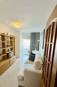 a bedroom with a large white bed and a couch at Ilumina Hostel Albufeira in Albufeira