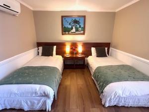 two twin beds in a room with a table at Hostal del Valle in Santa Cruz