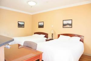 a hotel room with two beds and a desk at Athabasca Valley Inn & Suites in Hinton +45 photos