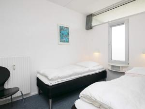 two beds in a room with a chair and a window at Apartment on a holiday park in Blokhus in Blokhus +33 photos