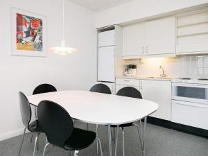 a white kitchen with a white table and chairs at Apartment on a holiday park in Blokhus in Blokhus