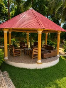 a gazebo with a red roof on a lawn at Kiki bay in Conakry