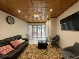 a living room with a leather couch and a tv at Instant Home in Luton