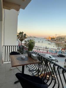 a balcony with a table and chairs and a view of the beach at EJ&A Coastal Suites in Marsaskala