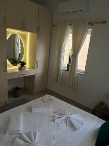 a bedroom with a bed with white sheets and a mirror at EJ&A Coastal Suites in Marsaskala
