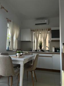 a kitchen with a white table and chairs in a room at EJ&A Coastal Suites in Marsaskala +4 photos