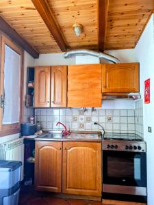 a kitchen with wooden cabinets and a sink and a stove at Casa vacanze Pievepelago in Pievepelago