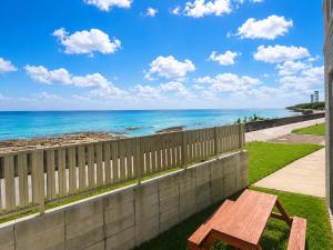 a wooden bench on a balcony with a view of the ocean at Wight Turtle Villa -Ishigaki Blue Retreat in Ishigaki Island