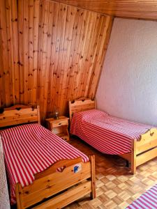 two beds in a room with wooden walls at Casa vacanze Pievepelago in Pievepelago